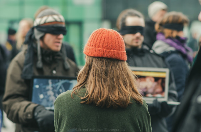 People standing in a Save Square, wearing a blindfold and holding up screens and signs